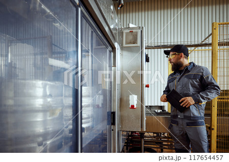 Brewery technologist, in full protective gear, carefully inspecting the production area, highlighting importance of safety and quality. Brewery technologist, in full protective gear, carefully inspecting the production area, highlighting importance of safety and quality. 117654457
