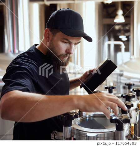 Dedicated technologist checking the brewing process, and equipment quality, maintaining perfect and well-equipped production. 117654503