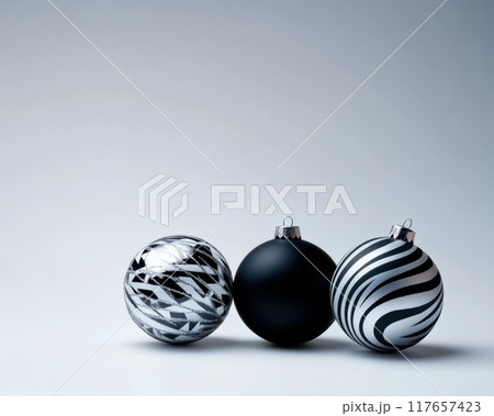 Three black and white Christmas ornaments are sitting on a white background Three black and white Christmas ornaments are sitting on a white background 117657423