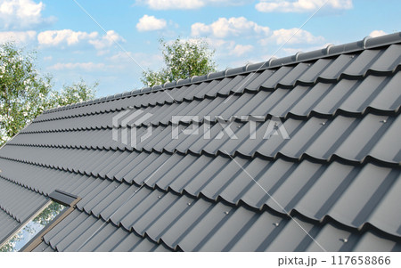 Close-up house roof with steel roofing sheet. Gray modular tile effect roof panel. Traditional metal shingle tiles. Profiled metallic corrugated pantile as clay or concrete slate. Building's covering 117658866
