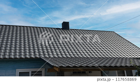 Close-up house roof with steel roofing sheet. Black modular tile effect roof panel. Traditional metal shingle tiles. Profiled metallic corrugated pantile as clay or concrete slate. Building's covering Close-up house roof with steel roofing sheet. Black modular tile effect roof panel. Traditional metal shingle tiles. Profiled metallic corrugated pantile as clay or concrete slate. Building's covering 117658869