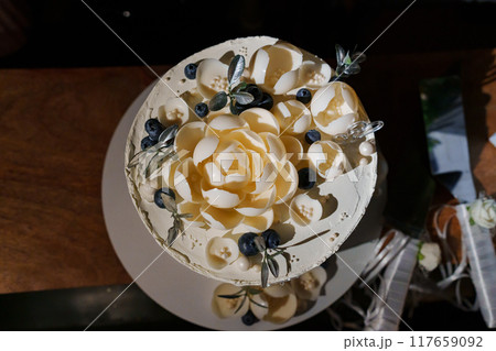 White wedding cake decorated with chocolate flowers and blueberries  117659092