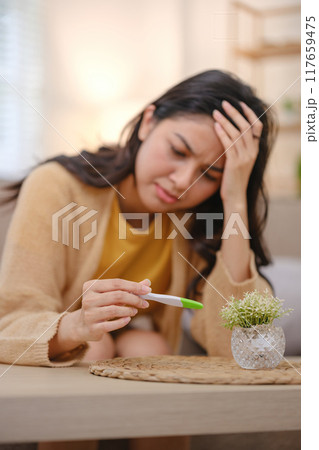 A woman is holding a pregnancy test and looking at it A woman is holding a pregnancy test and looking at it 117659475