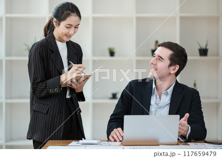 A woman is writing on a notepad while a man looks on A woman is writing on a notepad while a man looks on 117659479