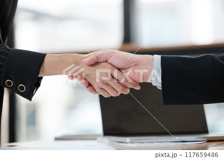 Two people shaking hands in a business setting 117659486