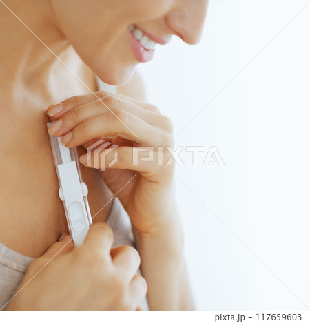 Closeup on happy young woman holding pregnancy test 117659603