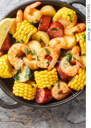 Classic shrimp boil that is a mixture of corn on the cob pieces, shrimp, smoked sausage and baby potatoes closeup. Vertical top view Classic shrimp boil that is a mixture of corn on the cob pieces, shrimp, smoked sausage and baby potatoes closeup. Vertical top view 117659958