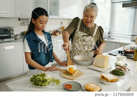 Grandma Cooking Breakfast For Her Granddaughter Grandma Cooking Breakfast For Her Granddaughter 117660809