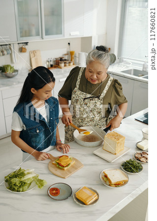 Grandmother Teaching Granddaughter To Cook Breakfast Grandmother Teaching Granddaughter To Cook Breakfast 117660821