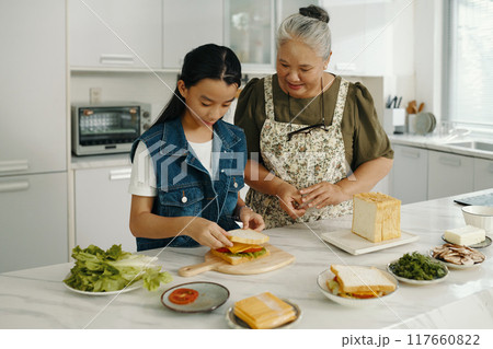 Girl Making Sandwich For Her Grandmother Girl Making Sandwich For Her Grandmother 117660822