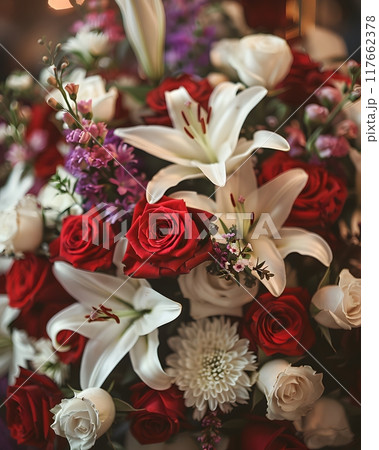 A lovely dark wood coffin adorned with roses, lilies, and carnations creates a lush display. Shot up close, the image captures intricate details, enhanced by soft, diffused light for a warm atmosphere A lovely dark wood coffin adorned with roses, lilies, and carnations creates a lush display. Shot up close, the image captures intricate details, enhanced by soft, diffused light for a warm atmosphere 117662378