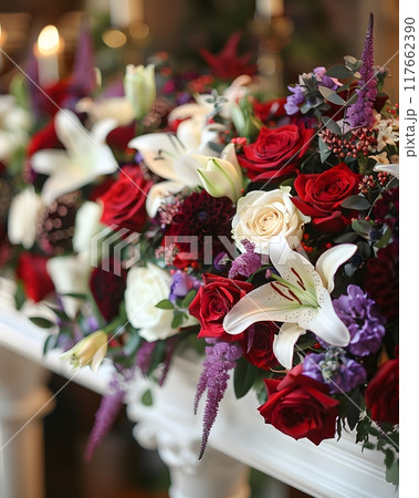 A lovely dark wood coffin adorned with roses, lilies, and carnations creates a lush display. Shot up close, the image captures intricate details, enhanced by soft, diffused light for a warm atmosphere 117662390