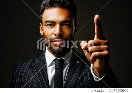 Businessman pointing upwards with confident little smile. focus on finger 117663602