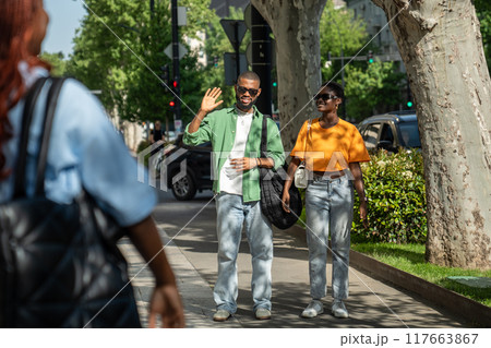 Happy black man waving hand to friend, greeting. Guy on date with girl, students meet classmate. Happy black man waving hand to friend, greeting. Guy on date with girl, students meet classmate. 117663867