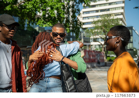 Joyful contented african american friends students hug meeting outside for walk, shopping together  117663873
