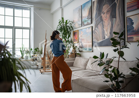 Woman looking at painting, Artist creative studio. Artist apartment gallery interior, Artwork hobby Woman looking at painting, Artist creative studio. Artist apartment gallery interior, Artwork hobby 117663958