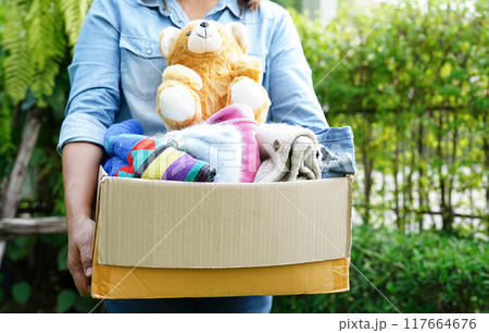 Volunteer collect cloth and doll in cardboard box to donate. 117664676