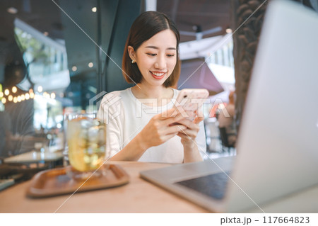 Business freelance asian woman using smartphone and laptop computer at cafe restaurant lifestyle 117664823