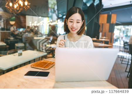 Asian woman using laptop and waiting at coffee cafe city break weekend balance lifestyle Asian woman using laptop and waiting at coffee cafe city break weekend balance lifestyle 117664839