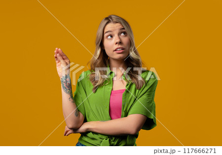 Irritated sarcastic woman showing bla-bla gesture hands on yellow background Irritated sarcastic woman showing bla-bla gesture hands on yellow background 117666271