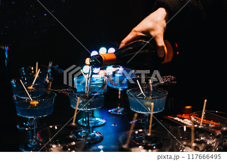 Bartender pouring cocktails over ice at a dimly lit bar. Nightlife, cocktail preparation, mixology, party atmosphere, bar scene. Bartender pouring cocktails over ice at a dimly lit bar. Nightlife, cocktail preparation, mixology, party atmosphere, bar scene. 117666495