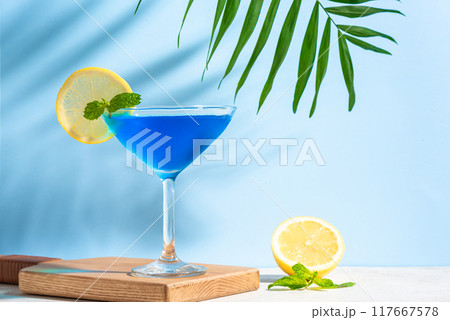 Blue summer cocktail with lemon and palm leaf Blue summer cocktail with lemon and palm leaf 117667578