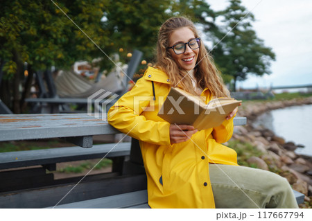 Young woman reading a book in the park. Relaxation, enjoying, solitude with nature. Young woman reading a book in the park. Relaxation, enjoying, solitude with nature. 117667794