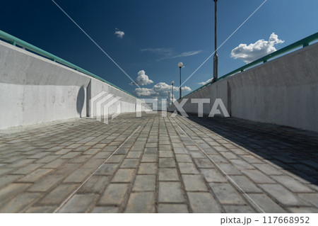 Paving slabs on a pedestrian bridge. The bridge is nearby. Clouds in the sky 117668952