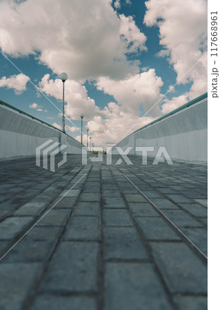 Paving slabs on a pedestrian bridge. The bridge is nearby. Clouds in the sky Paving slabs on a pedestrian bridge. The bridge is nearby. Clouds in the sky 117668961