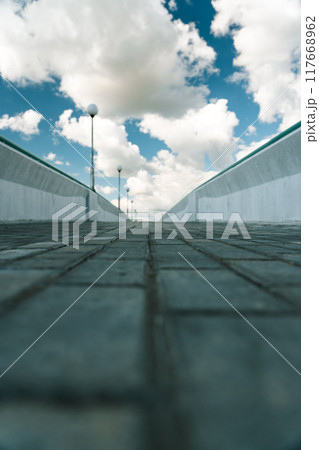 Paving slabs on a pedestrian bridge. The bridge is nearby. Clouds in the sky Paving slabs on a pedestrian bridge. The bridge is nearby. Clouds in the sky 117668962