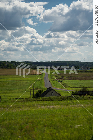 An asphalt road in the distance between fields. Thick clouds over the road An asphalt road in the distance between fields. Thick clouds over the road 117668967