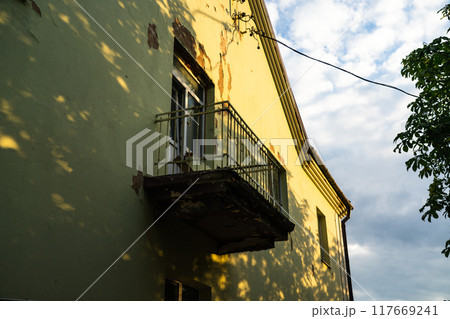 Balcony with access to the street, in an old house, with peeling plaster 117669241