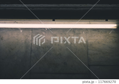 A fluorescent lamp illuminates a marble wall in the subway 117669270