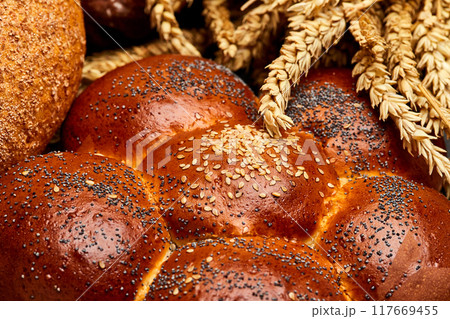 Assortment of freshly baked bread loaves with wheat stalks, tradition and artisanal baking Assortment of freshly baked bread loaves with wheat stalks, tradition and artisanal baking 117669455