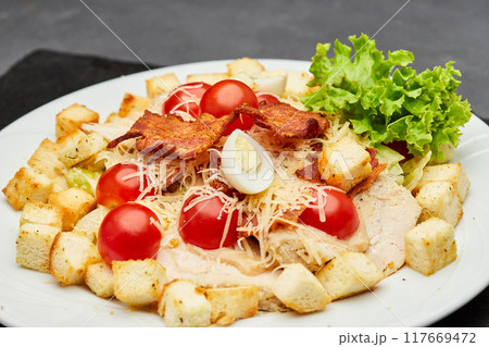 Fresh Caesar salad with cherry tomatoes, crispy bacon, and parmesan cheese, perfect for a light meal 117669472