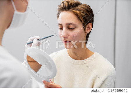 Aesthetician applies skincare treatment to client in a spa setting 117669642
