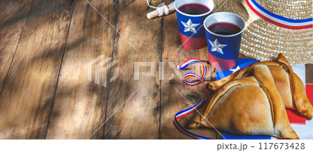 Chilean independence day concept. fiestas patrias. Tipical baked empanadas, wine or chicha, fat and play emboque. Decoration for 18 september party day, wooden background, top view 117673428