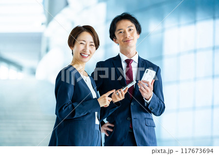 スマホを持った男性社員と女性社員 ビジネスイメージ スマホを持った男性社員と女性社員 ビジネスイメージ 117673694