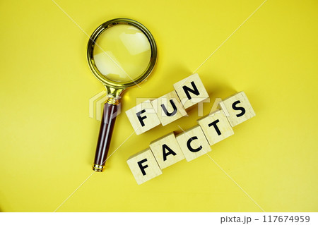 Fun Facts with wooden blocks alphabet letters and Magnifying glass on yellow background 117674959
