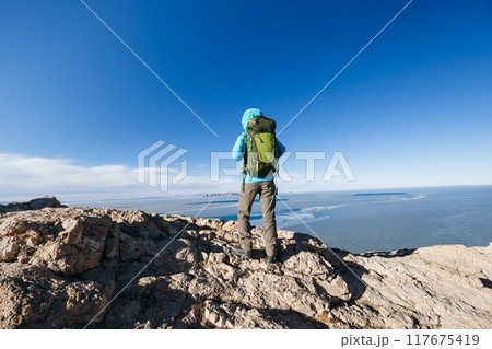 Woman hiker enjoy the view on mountain top cliff edge at lakeside 117675419