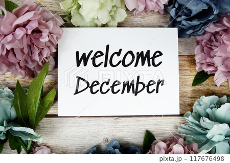 Welcome December text on paper card with flowers frame top view on wooden background Welcome December text on paper card with flowers frame top view on wooden background 117676498