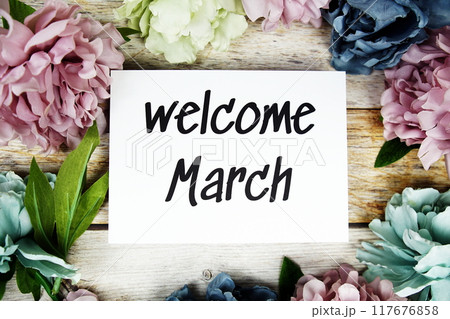 Welcome March text on paper card with flowers frame top view on wooden background Welcome March text on paper card with flowers frame top view on wooden background 117676858