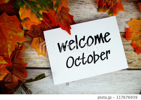 Welcome October text with maple leaf decoration top view on wooden background 117676939
