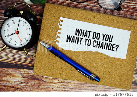What do you want to change? text written on paper torn with pen top view on wooden background 117677613