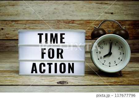 Time for Action text on LED lightbox with alarm clock on wooden background 117677796