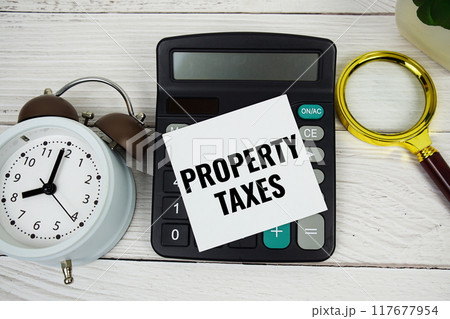 Property Taxes text message with calculate, alarm clock and magnifying glass on wooden background Property Taxes text message with calculate, alarm clock and magnifying glass on wooden background 117677954