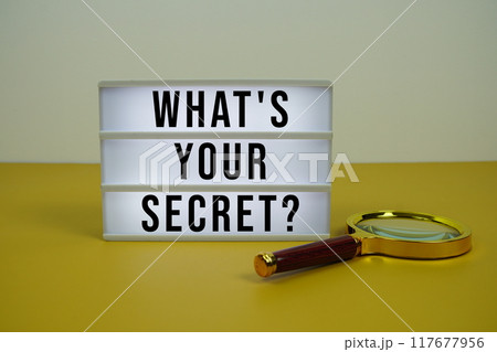 What's Your Secret? text on LED lightbox with magnifying glass on yellow background 117677956