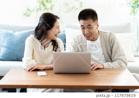 リビングでノートパソコンを使うシニア夫婦 117678619