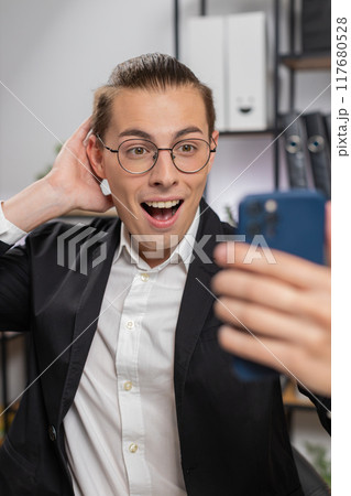Happy amazed young Caucasian businessman working on smartphone shocked by sudden victory at home Happy amazed young Caucasian businessman working on smartphone shocked by sudden victory at home 117680528