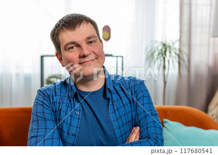 Portrait of happy Caucasian man sitting on couch looking at camera and smiling relaxing at home 117680541